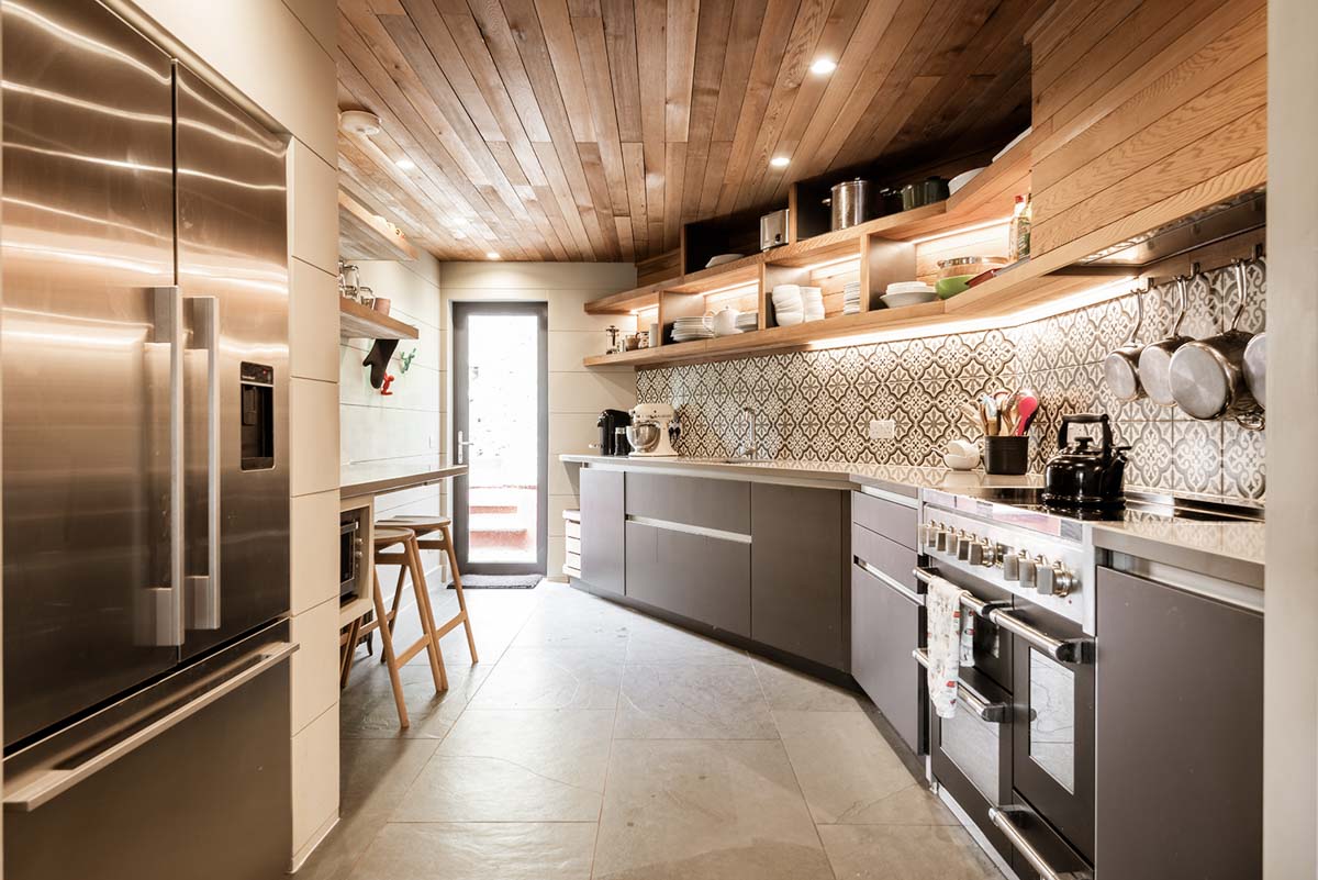Cranked kitchen with high level open shelving and timber ceiling